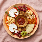POLKA LUKA large resin Luna serving plate in orange and red, styled with cheese, fruit, and crackers on a linen cloth