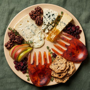 POLKA LUKA large beige resin Luna serving plate with tortoiseshell salad hands, styled with a cheese and fruit platter.